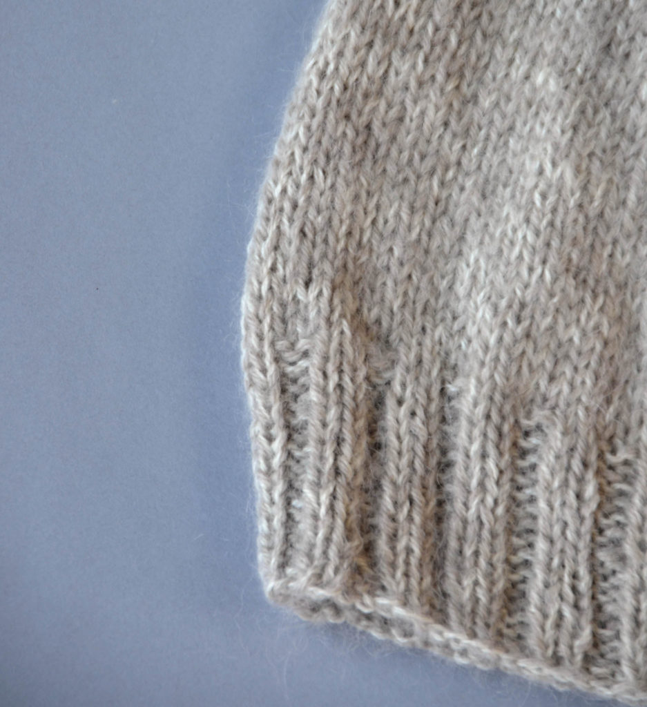 Closeup image of the ribbed brim and body of a knitted hat