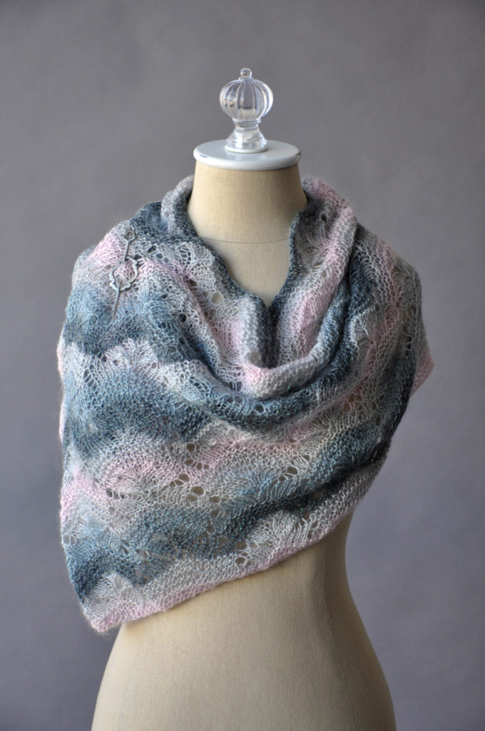 Knitted pink and gray lace cowl pinned at the shoulder with a pewter shawl pin
