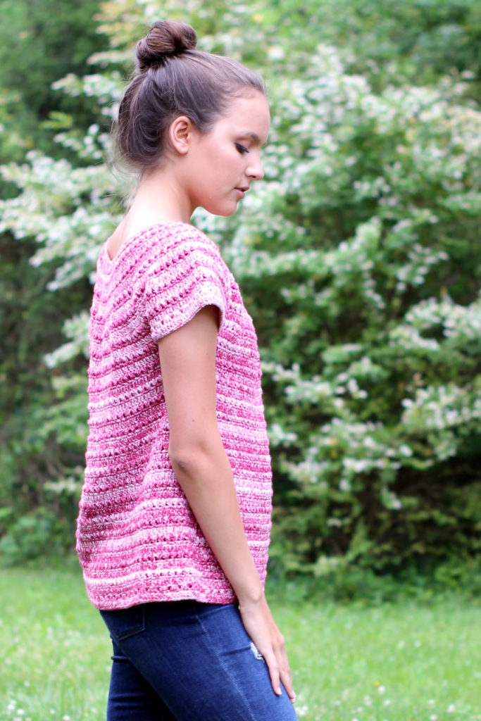 Side view of woman wearing red crochet top standing outdoors