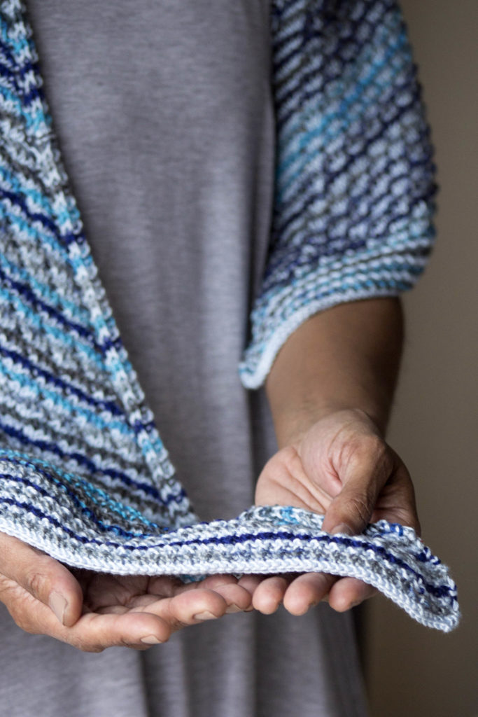 Woman's hands holding edge of shawl knitted with i-cord bind-off