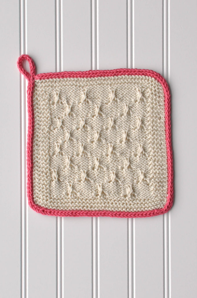 cream knitted washcloth with pink loop at corner