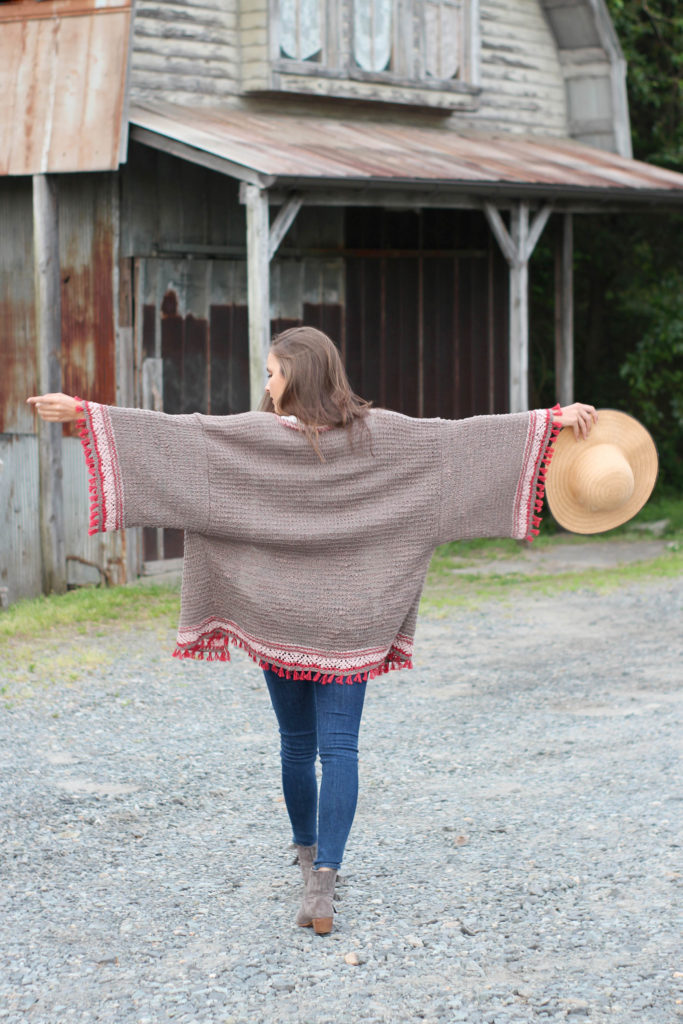 Woman walking away from camera, arms outstretched to show wide sleeves of knit kimono