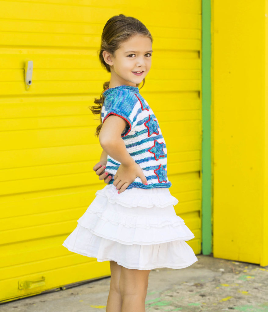 Girl in white ruffled skirt and knitted top against yellow background