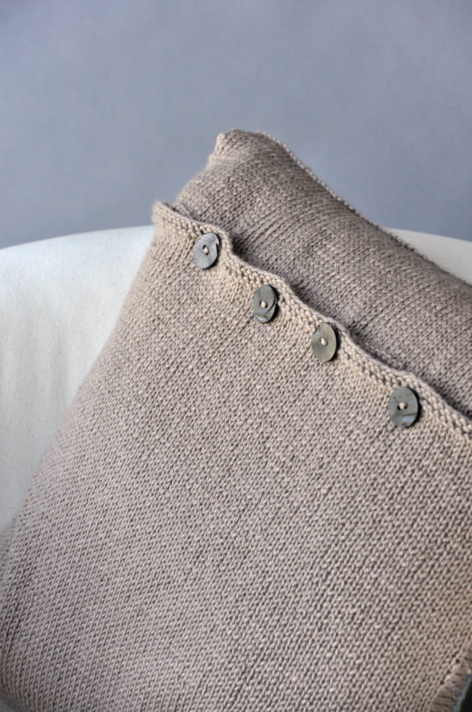 Tan knitted pillow showing button closure