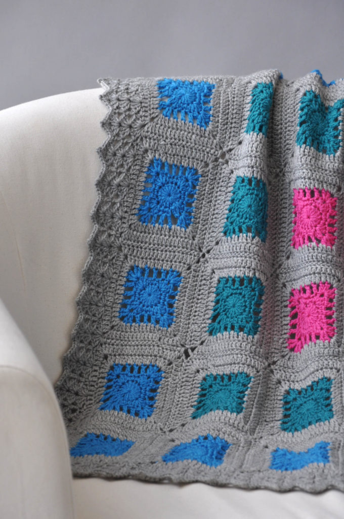 Gray crochet blanket draped over chair back