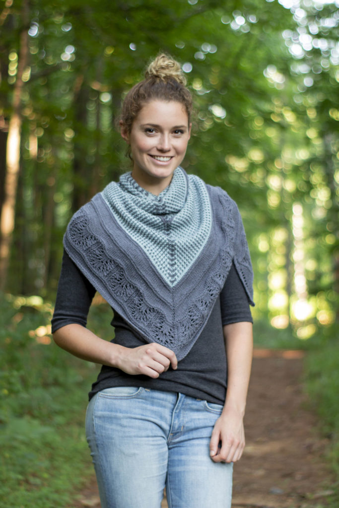 Woman in woods wearing blue and gray knit shawl