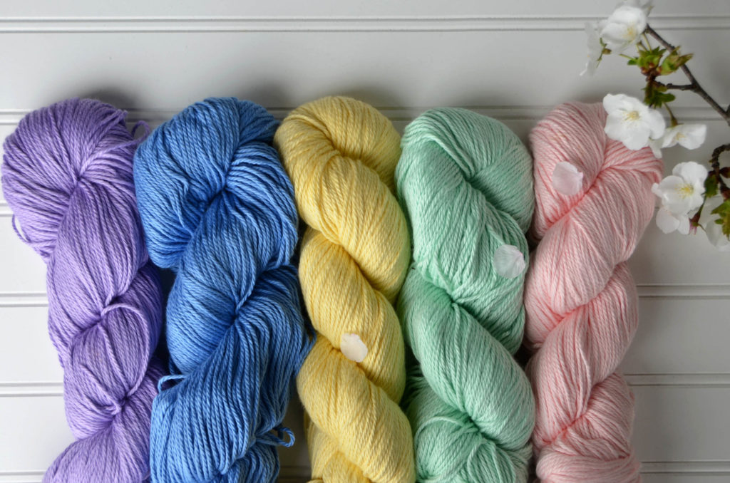 Five pastel hanks of Cotton Supreme DK with a blossoming cherry branch