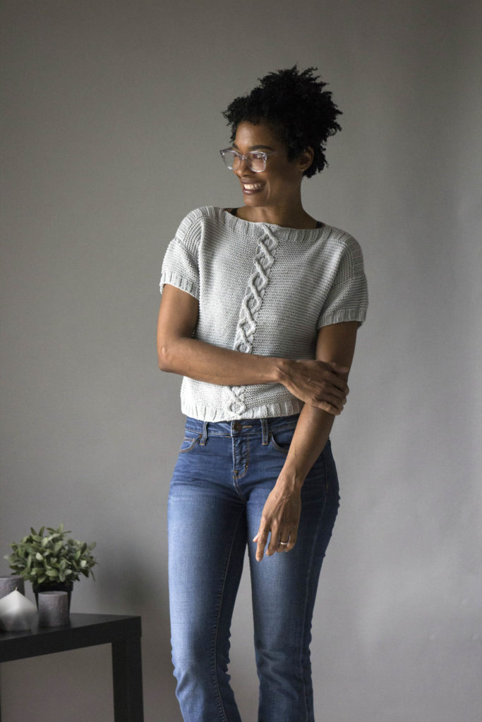 Smiling woman wearing light blue knitted Cora Crop tee in Bamboo Pop yarn