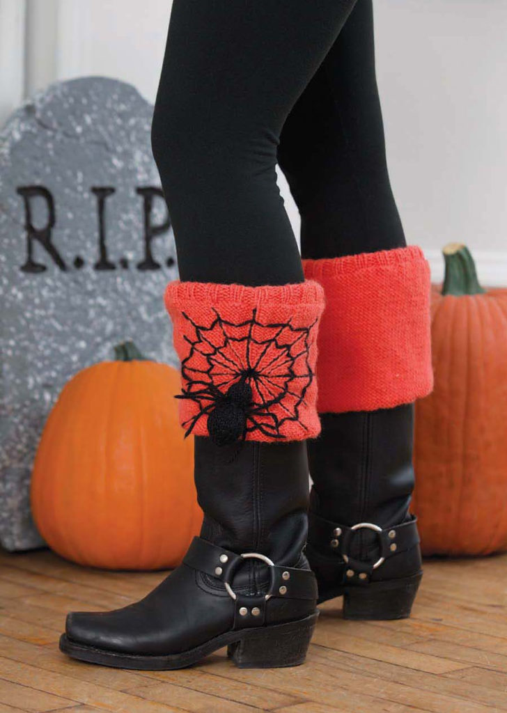 Orange knitted boot toppers with spiderweb embroidery