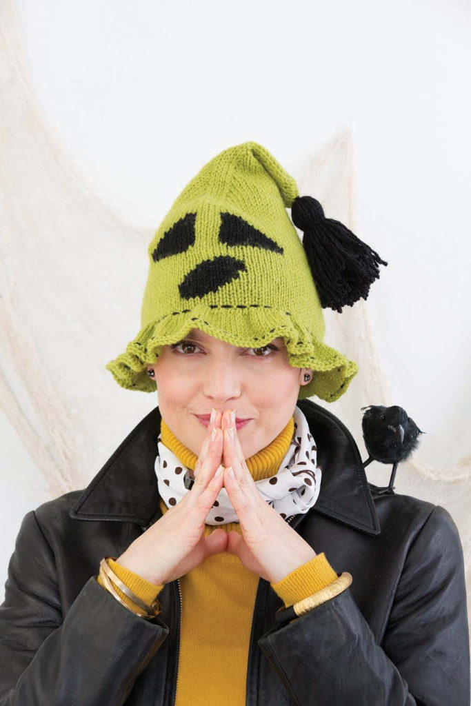 Woman wearing light green knit hat with ghost face design