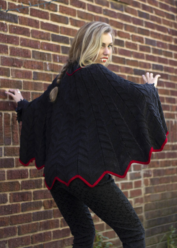 Image of woman in knitted black cape looking over her shoulder
