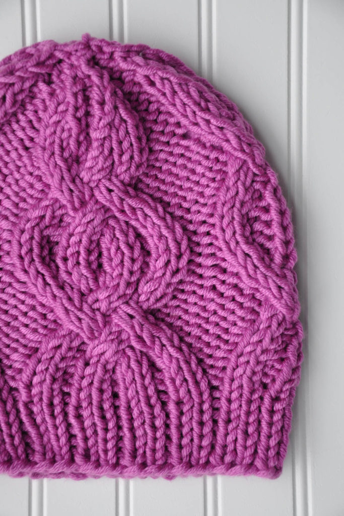Closeup view of fuchsia cabled hat knit in Uptown Super Bulky