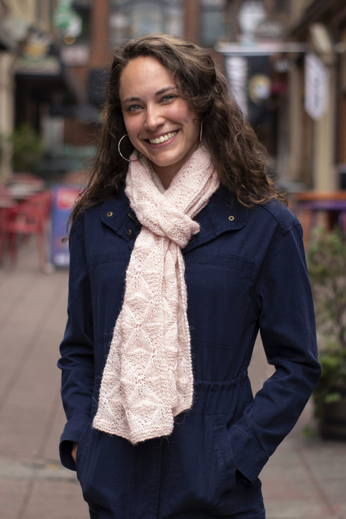 Smiling woman wearing blue overcoat and pink knitted scarf