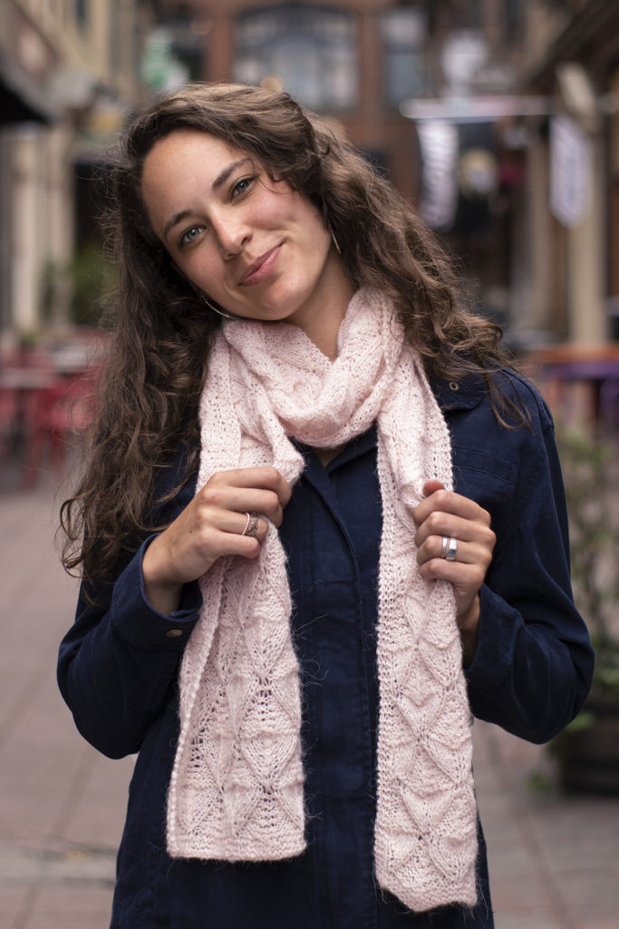 woman wearing light pink scarf knit in Odette yarn