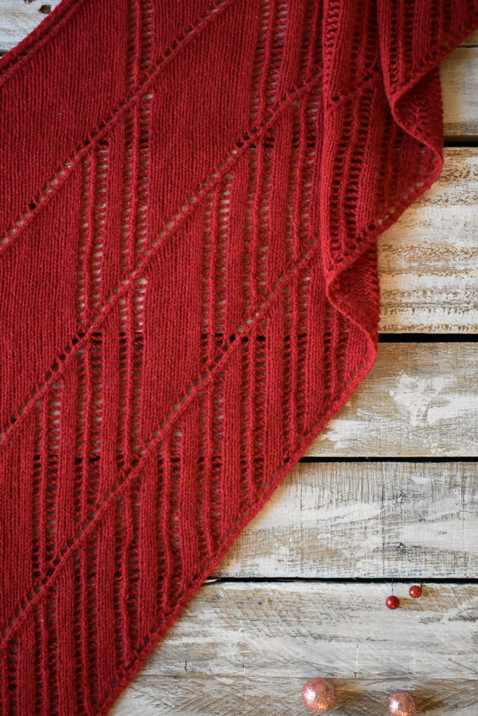 Detail of a red, lace shawl knit in Fibra Natura Cashmere Lusso.
