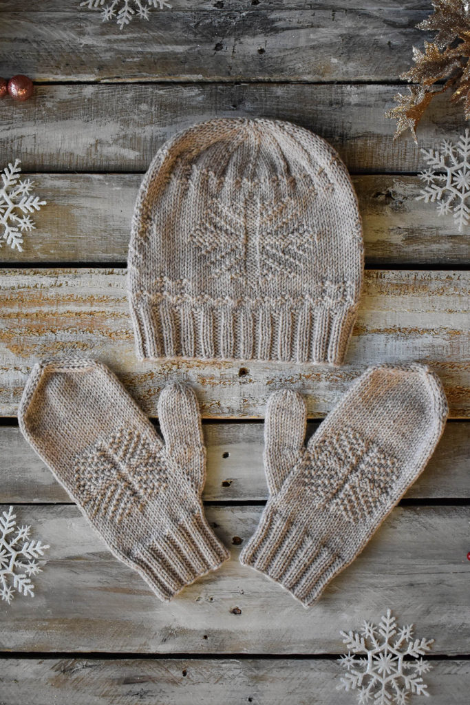 A pair of mittens and a hat with a snowflake motif knit in Universal Yarn Deluxe DK Superwash.