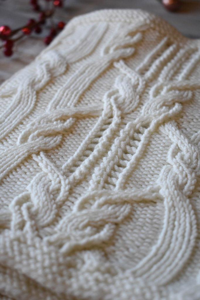 Detail of a white cowl featuring cables and lace knit using Fibra Natura Dona.