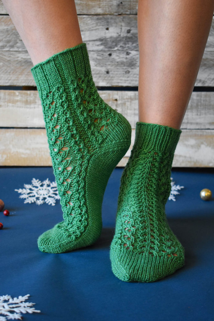 A model wearing a pair of green socks knit using Universal Yarn Bella Cash.