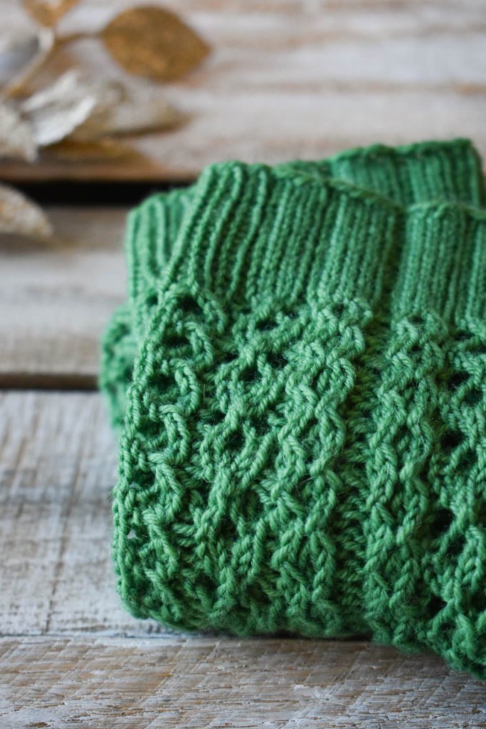 A close-up of a green pair of socks knit using Universal Yarn Bella Cash.