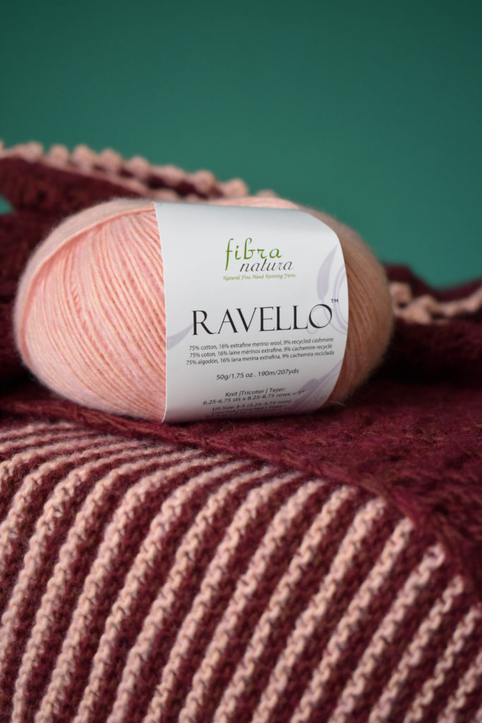 A ball of Fibra Natura Ravello placed on top of a shawl. 