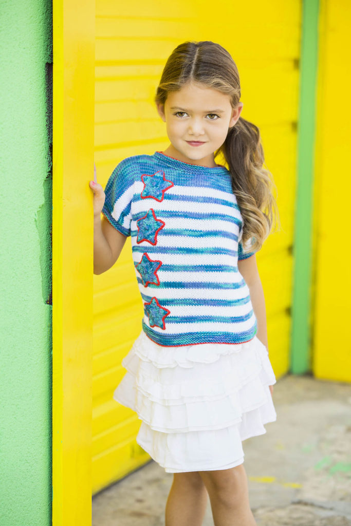 Little girl wearing knit striped top with applique stars in Bamboo Pop
