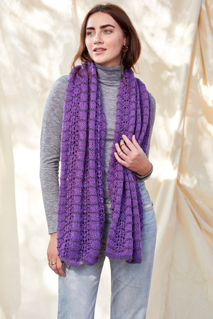 Woman wearing scarf knit in purple Deluxe Worsted yarn.