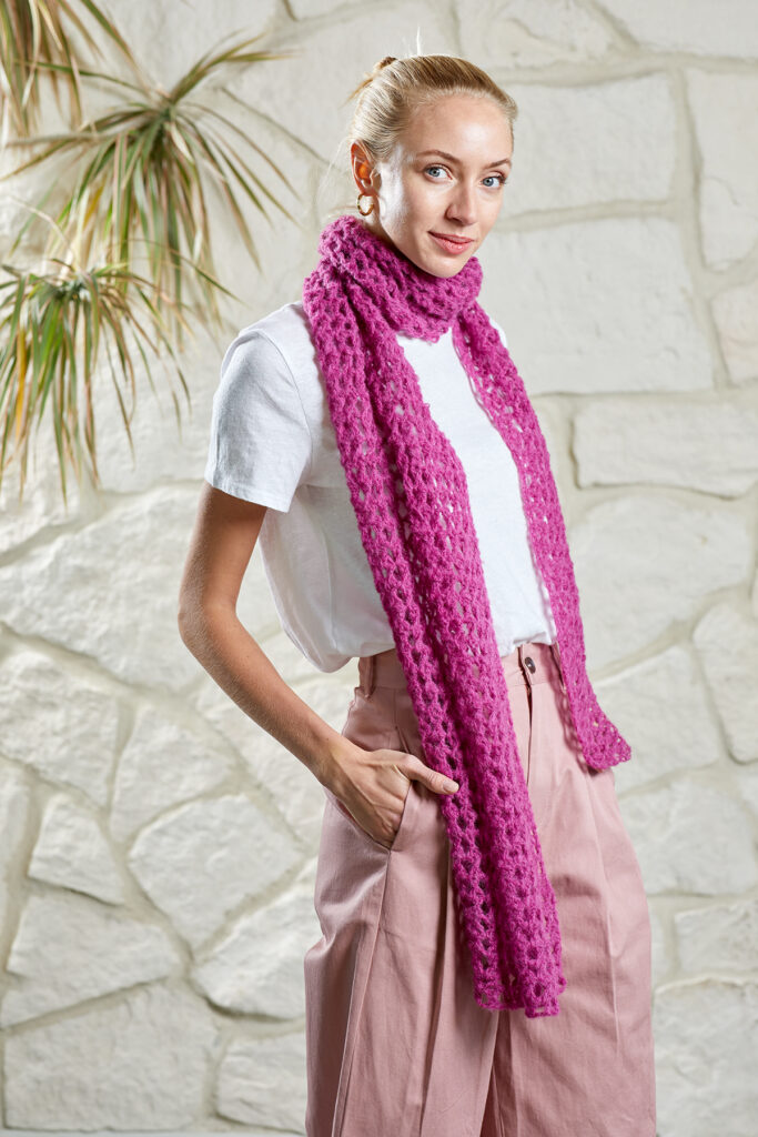 Woman wearing pink scarf-style shawl crocheted in Penna