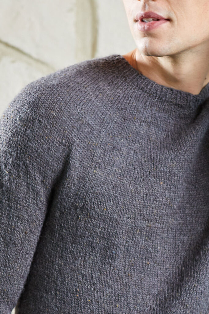 Shoulder detail of young man wearing gray Damascus sweater knit in Kingston Tweed