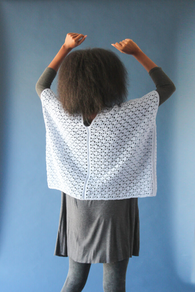 Rear view of woman wearing poncho crocheted in Papyrus yarn.