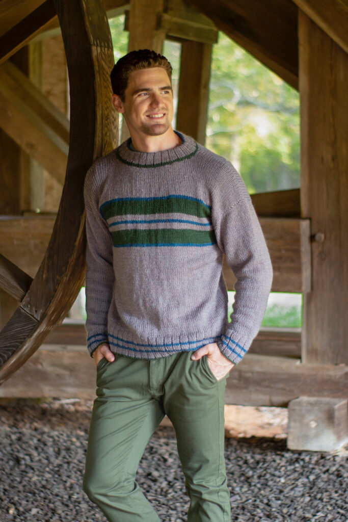 Man wearing grey sweater with green and blue stripes
