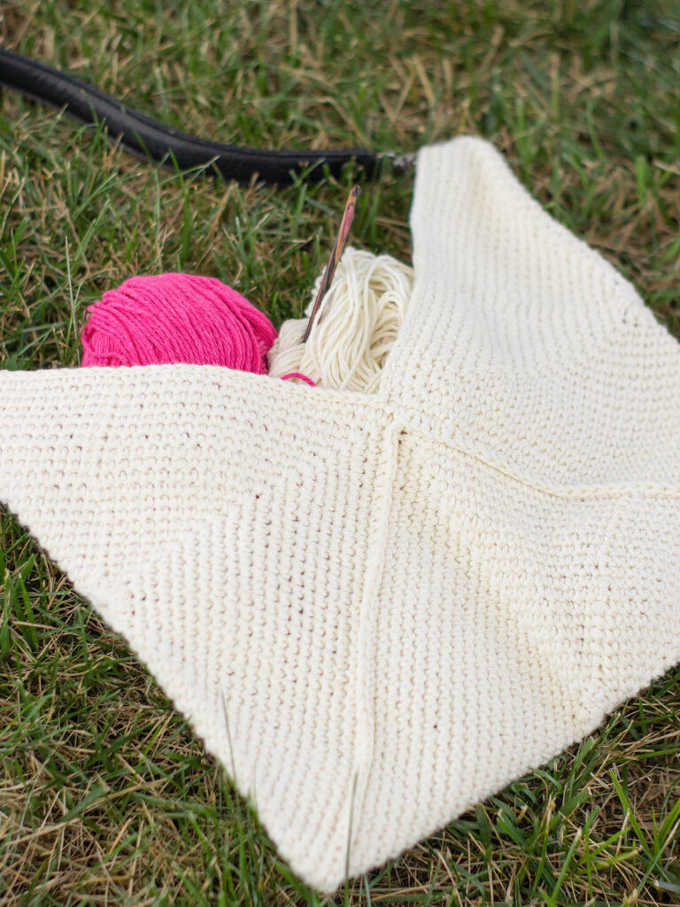 Image of cream-colored crocheted purse lying in grass,
