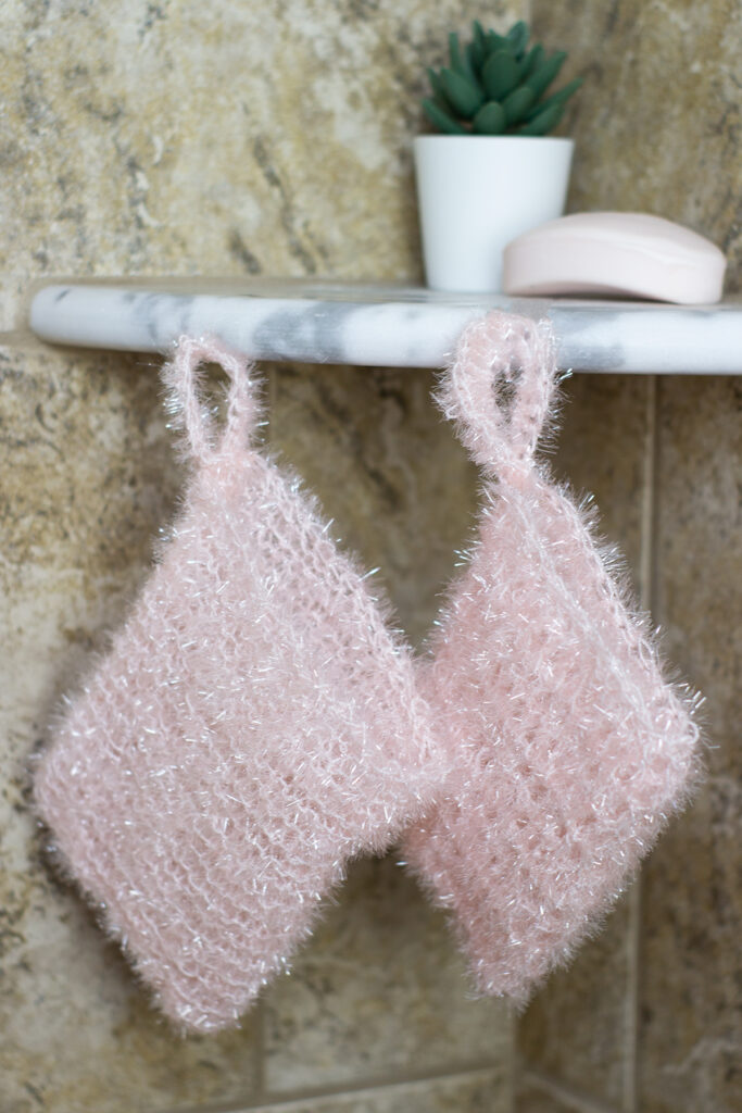 image of two light pink bath scrubbies, one knitted and one crocheted