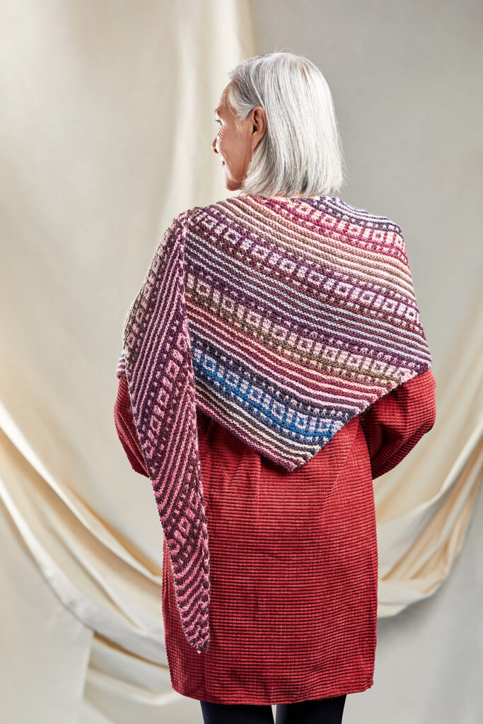 rear view of a woman wearing a colorful striped knitted shawl