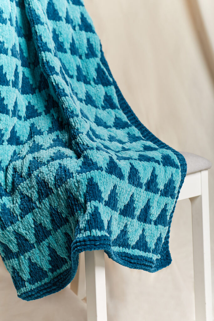 Closeup of knitted chenille throw in aqua with triangles motif.