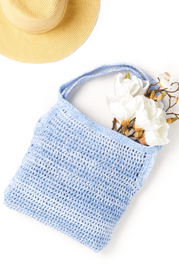 Image of blue crocheted tote holding bouquet of white flowers