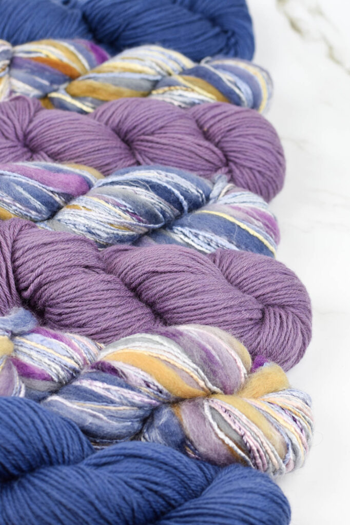 Skeins of blue and purple Deluxe Worsted and Bamboo Bloom Handpaints yarn