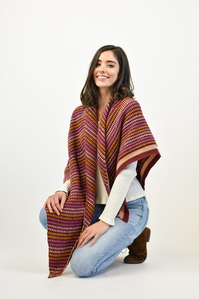 Woman crouched on one knee wearing Spice Market Shawl crocheted in Uni Merino