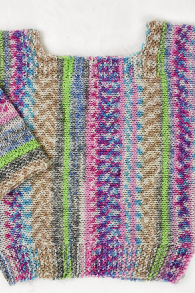 A close-up of the patterning and neckline of the hand knitted Peekaboo Pullover. 