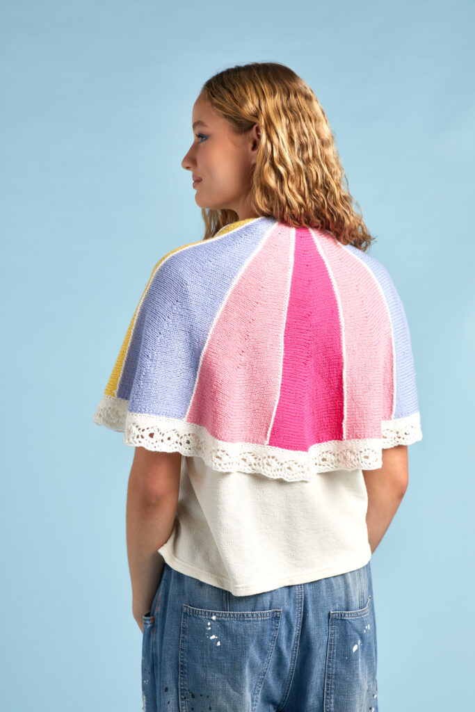 Photo of a person wearing the Color Wheel Shawl in front of a blue background