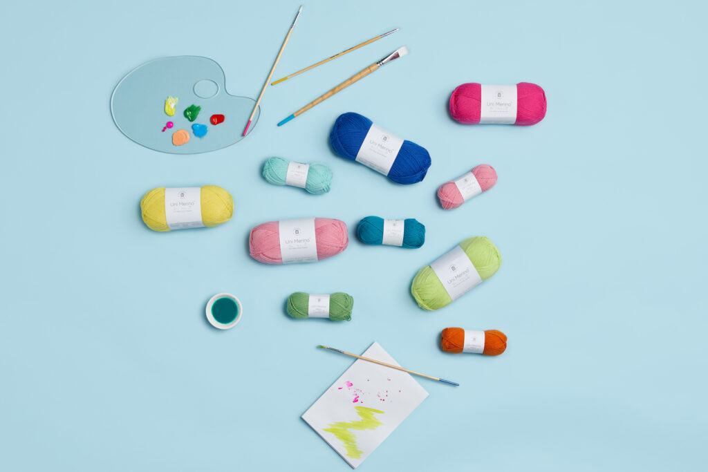 Photo of Uni Merino and Uni Merino Mini on a blue background with paint brushes and paint